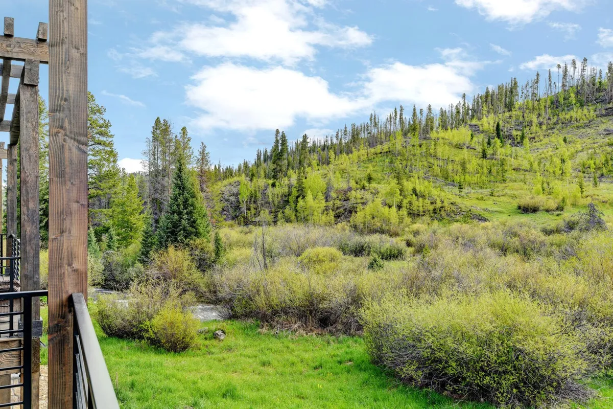 A tranquil view of lush greenery, a flowing stream, and a distant hillside. The natural landscape is inviting and highlights scenic trails that can be explored for hiking, biking, or peaceful moments by the river.