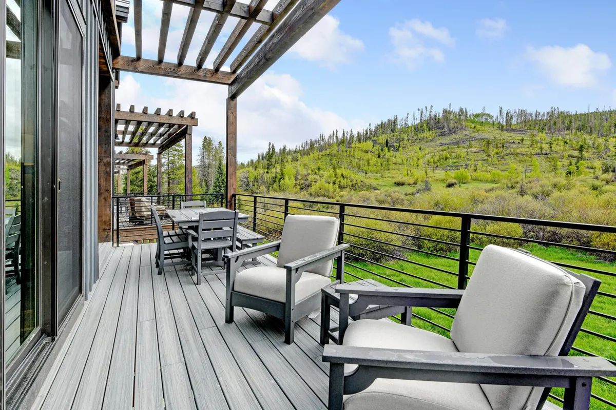 A tranquil outdoor seating area beneath a pergola offers panoramic mountain views. Comfortable chairs and a relaxed setting make it an ideal space for unwinding, reading, or catching up with friends, with the dramatic Rockies as a backdrop.