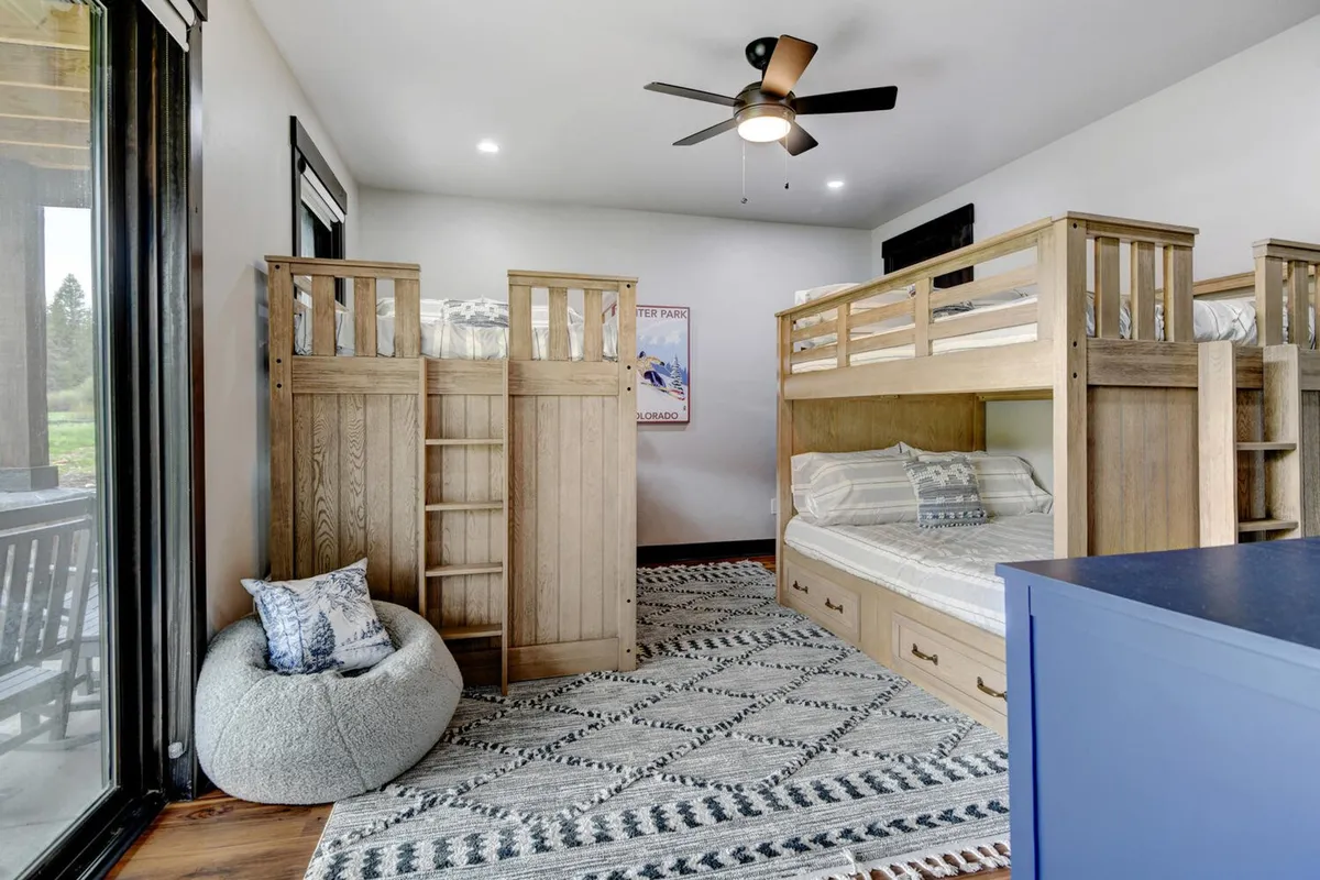 A playful, family-friendly bunk room with multiple bunk beds, a cozy bean bag chair, and a cheerful area rug. The setup is ideal for children or groups, creating a fun and relaxed environment for sleep and play.
