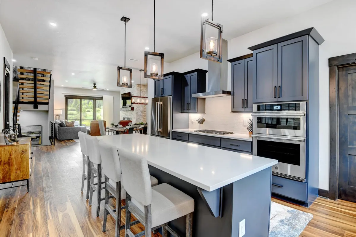 A bright, contemporary kitchen showcasing a sleek island with bar seating, gleaming stainless steel appliances, and stylish pendant lights overhead. The open layout is perfect for both casual brunches and sophisticated dinner parties, emphasizing the kitchen's role as a social hub.