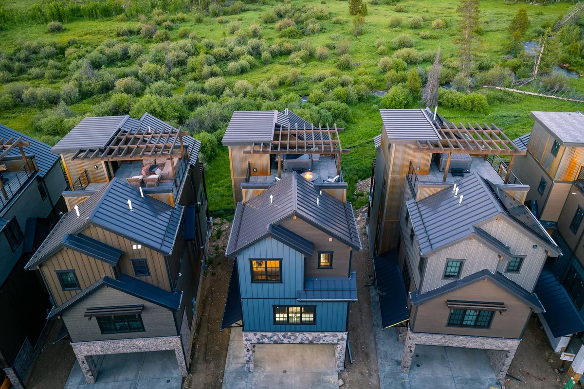 The exterior of a modern building set among lush green surroundings, featuring rooftop terraces ideal for gathering or relaxing. The architecture is inviting, signaling both a destination and a welcoming community space.